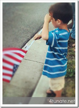 little boy salutes fallen solider and waves flag