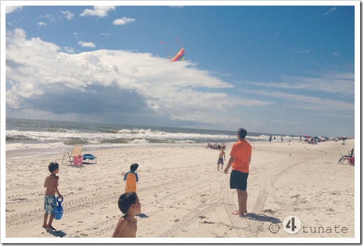 flying a kite at the beach with boys